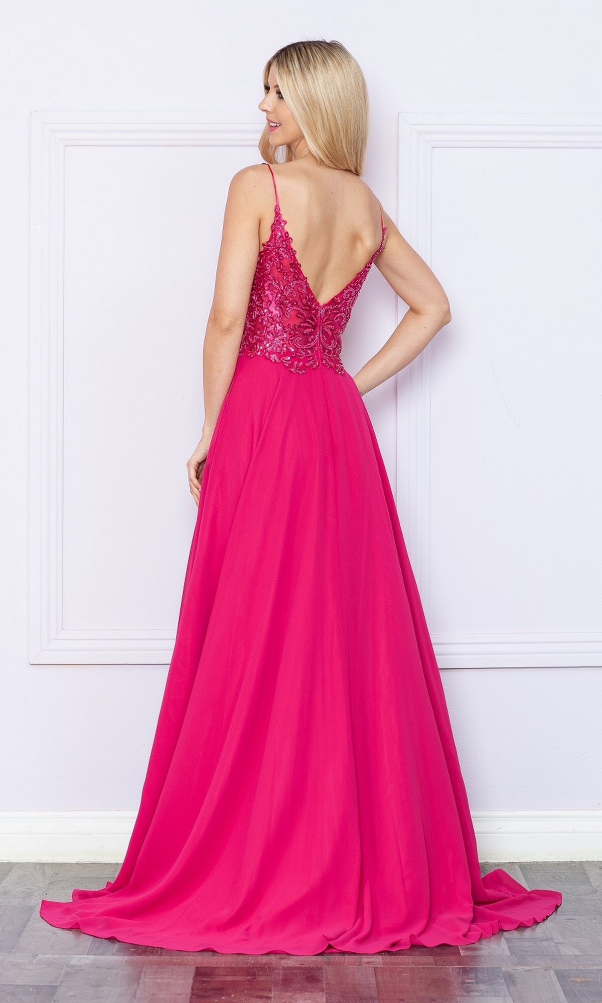 A woman faces away in the Beaded-Bodice Long A-Line Prom Dress 9366, featuring bright pink fabric, a sparkly beaded lace bodice, spaghetti straps, and a V-shaped open back.